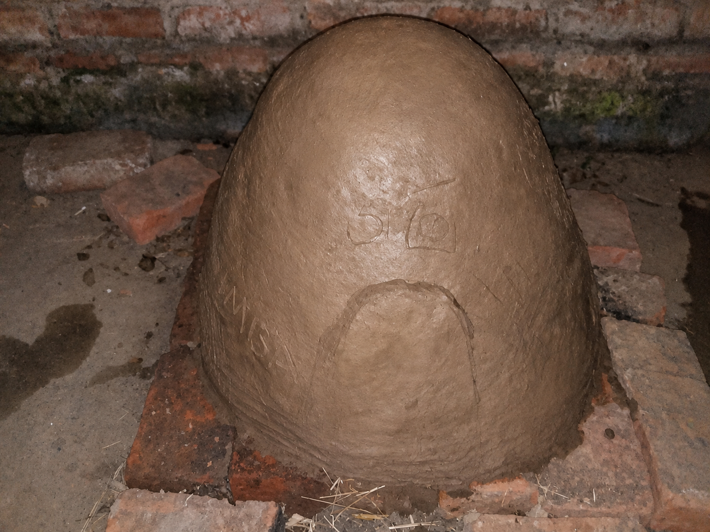 The first clay and sand layer smoothed over the oven dome with a doorway marked out