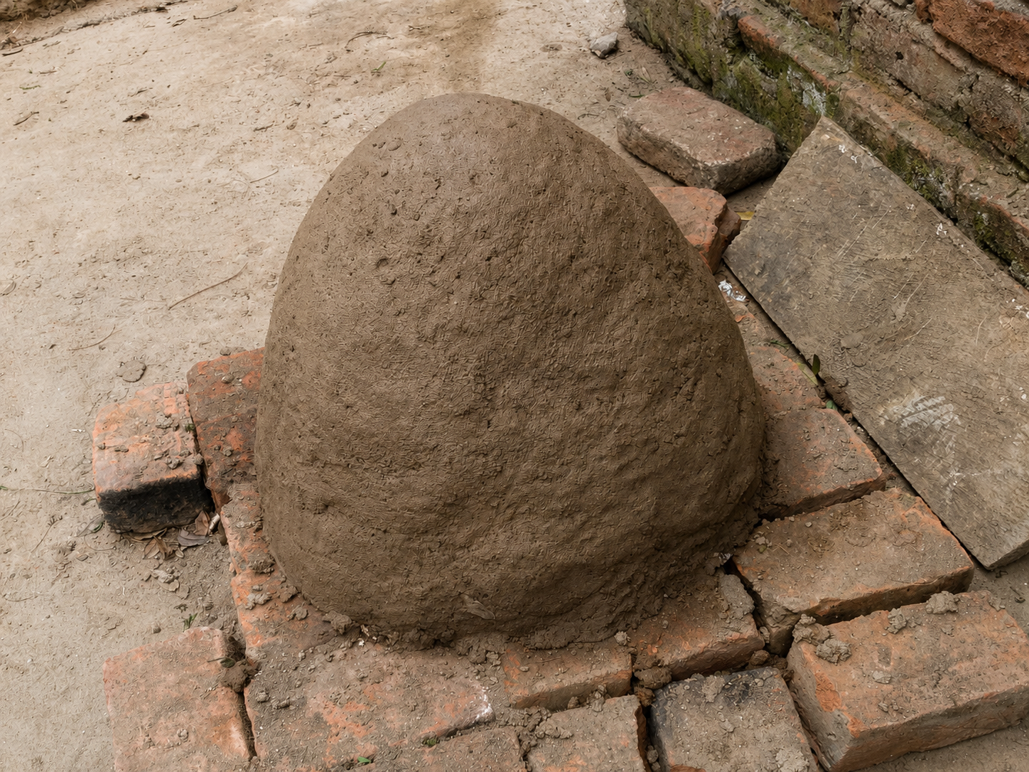 The hardened clay shell drying on top of the brick oven base