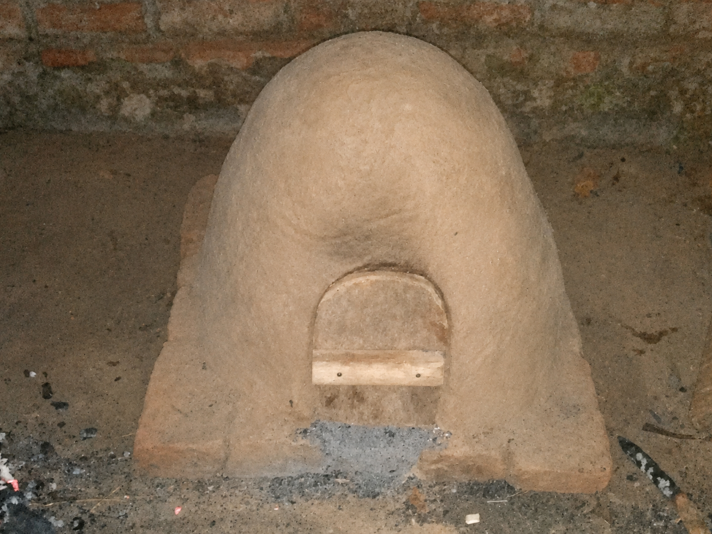 The finished earthen oven with a small wooden door fitted into the opening